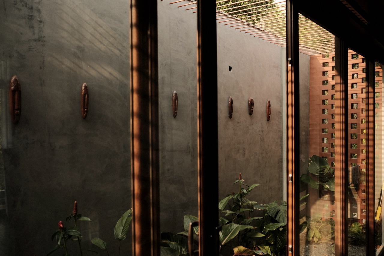 Carved wooden masks on a lime-washed wall, seen through glazing