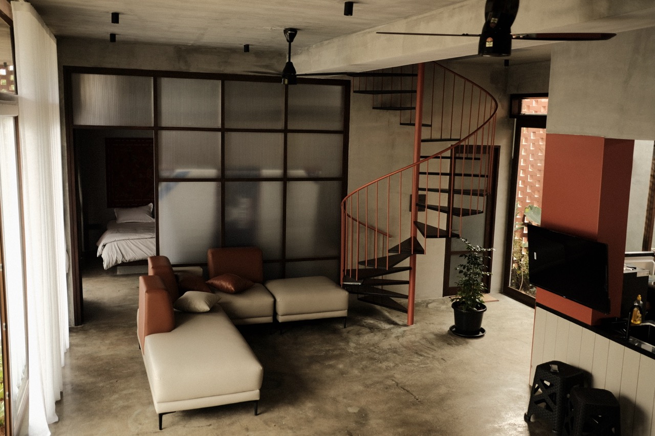 The living room with its rust-red spiral stair and reeded glass partition